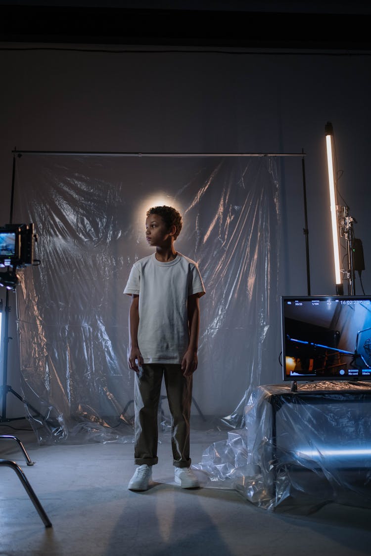 Boy Un White Shirt Standing Near TV Monitor