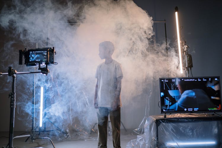 A Boy Standing On A Smoke Near A Screen