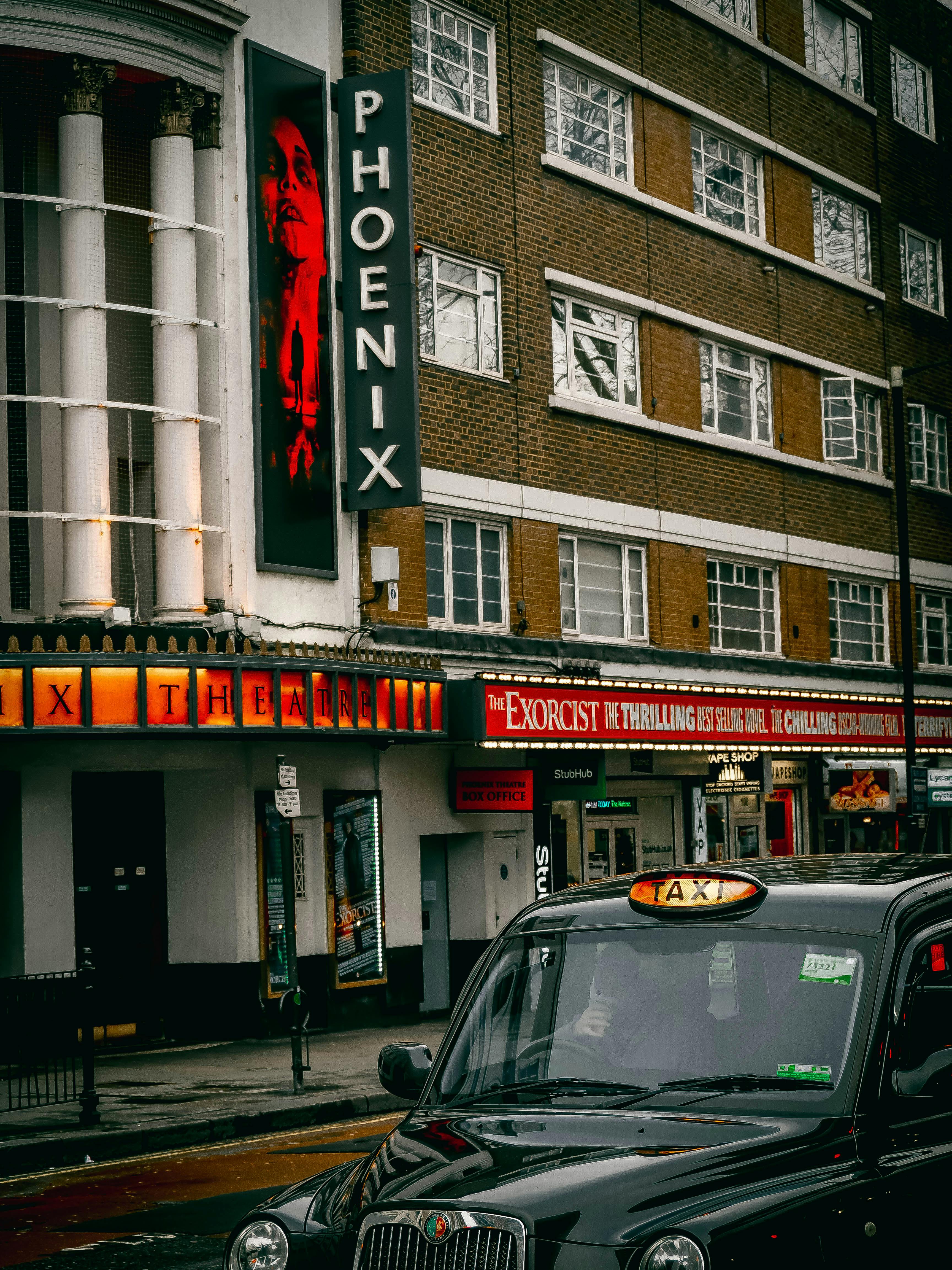 Free Capture of The Phoenix Theatre and iconic black taxi in London's West End, showcasing vibrant city life. Stock Photo