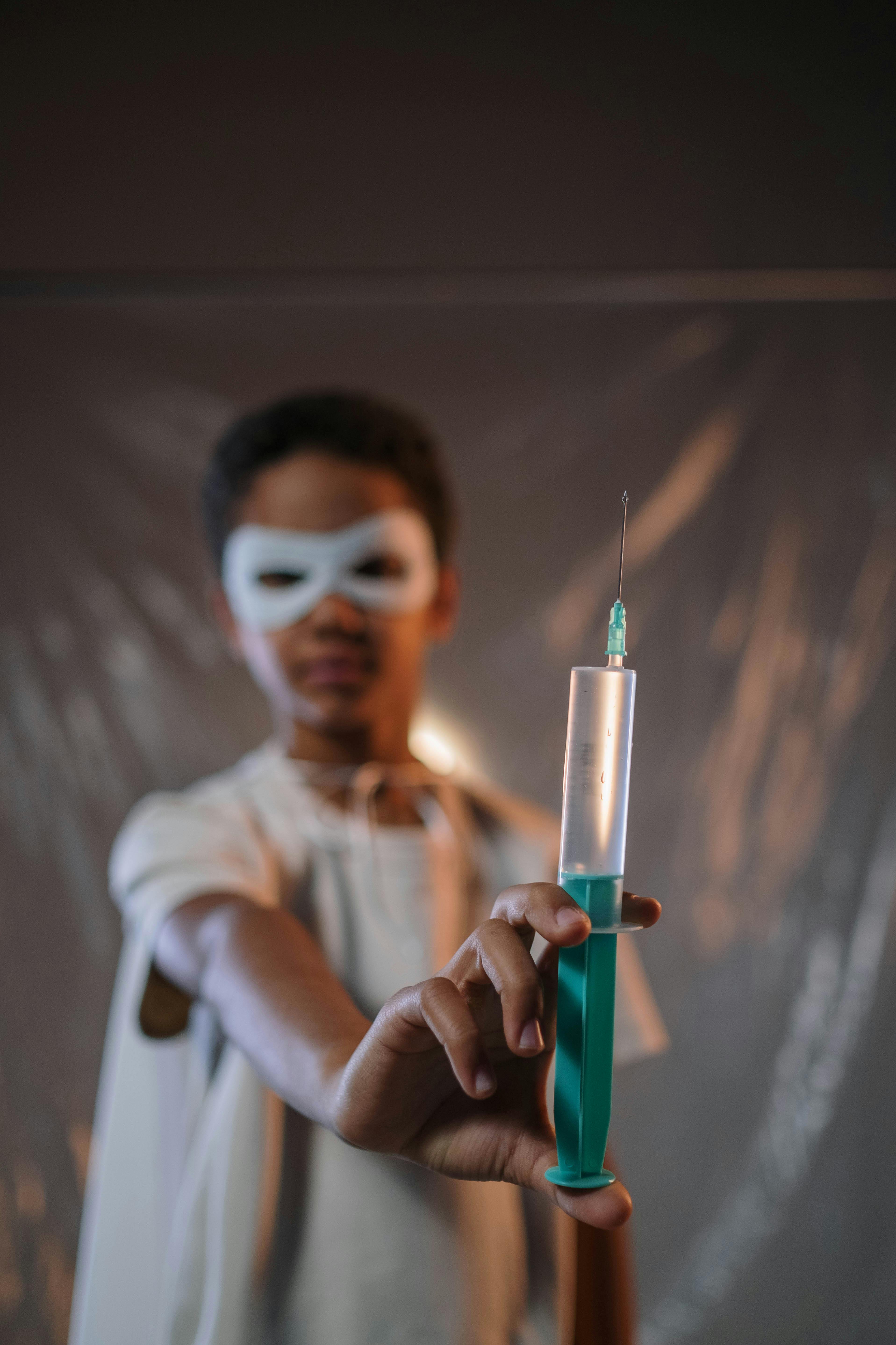 a boy wearing a mask holding a syringe