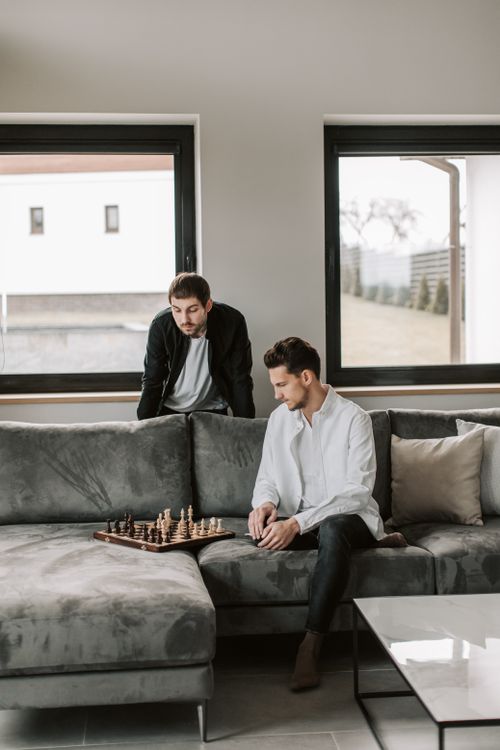 Free Two men engrossed in a chess game on a cozy sofa in a modern living room. Stock Photo