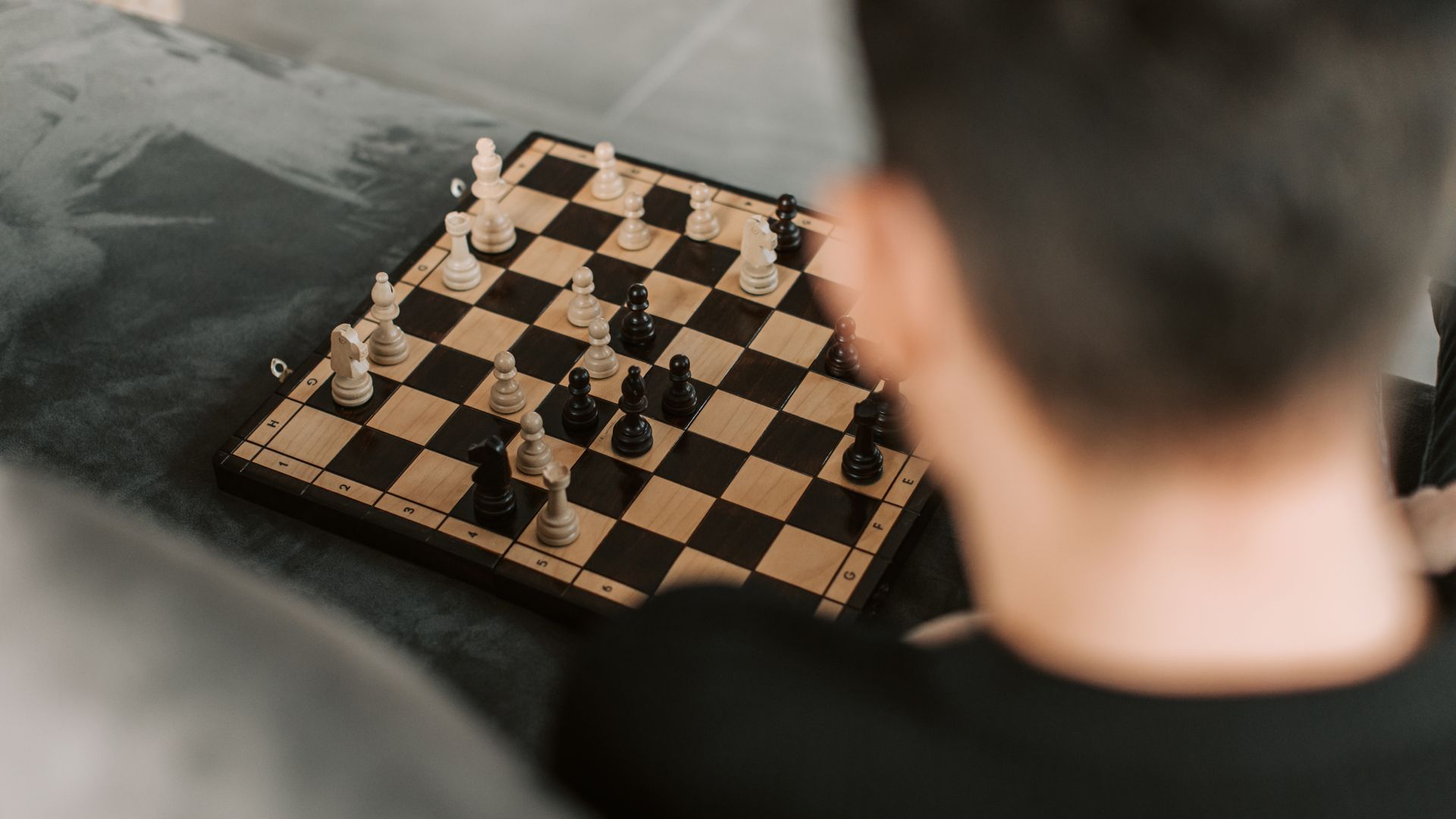 A person intensely focusing on a chess game. Close-up, board view, strategic play — beginners unlocking strategies