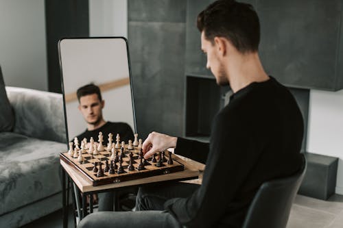 A Man Playing Chess In Front of a Mirror 