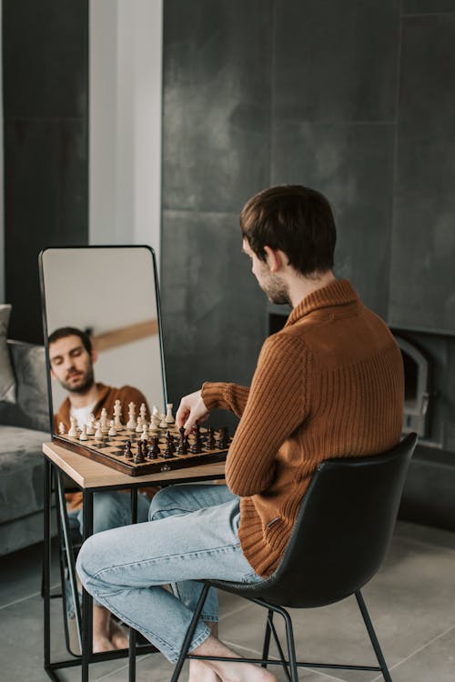 Man in Brown Jacket Sitting on Black Chair Playing Chess