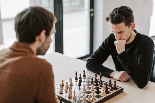 Free Two men deeply focused on a strategic chess game indoors, showcasing concentration and leisure. Stock Photo