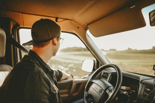 Free A man enjoys a relaxed drive through the countryside on a sunny day, looking out onto the scenery. Stock Photo