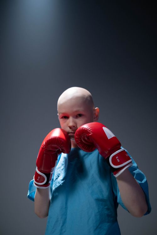 Free Bald young person in red boxing gloves showing resilience and strength indoors. Stock Photo