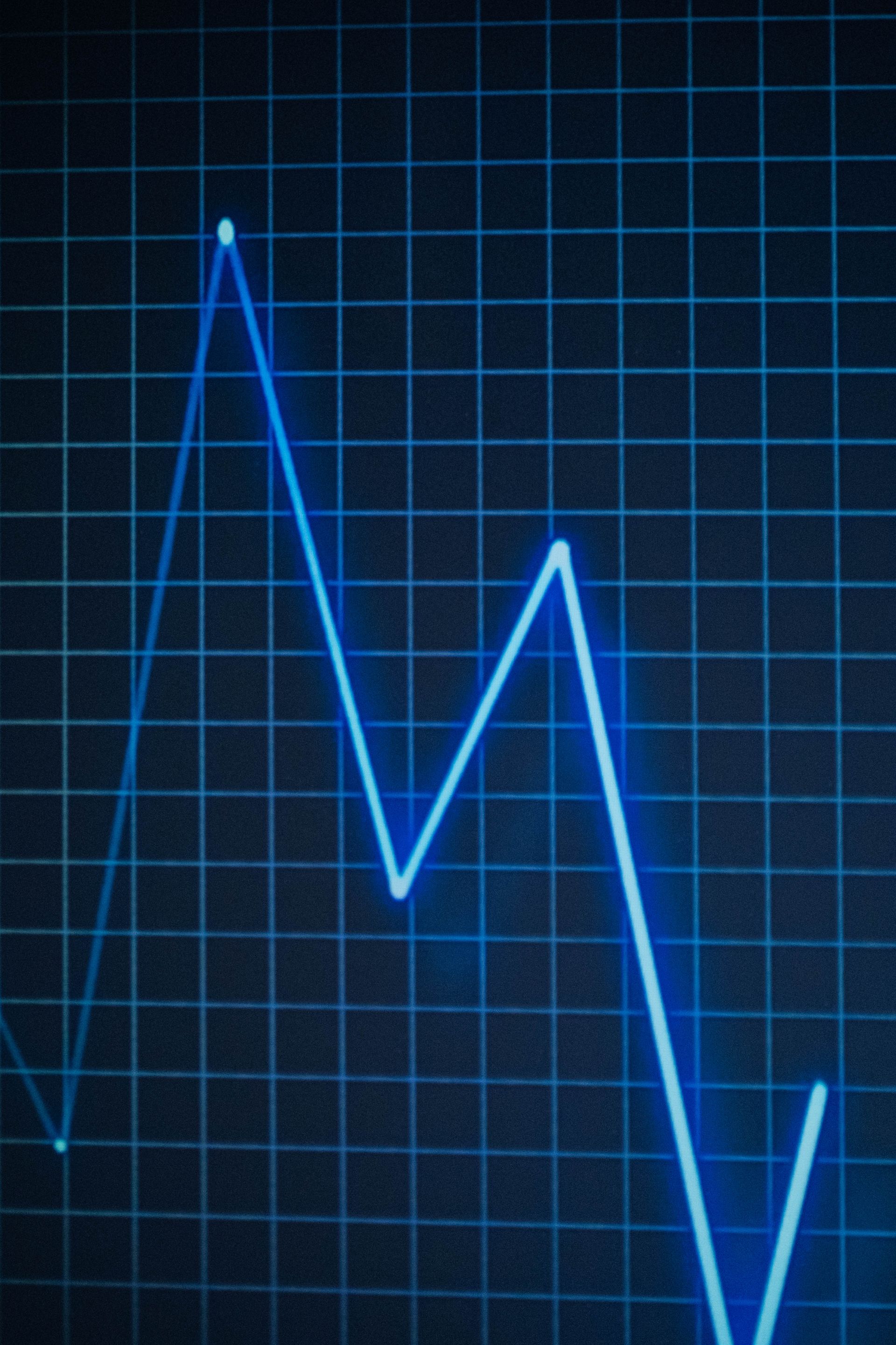 Close-up of a neon blue line chart on a grid, symbolizing data trends