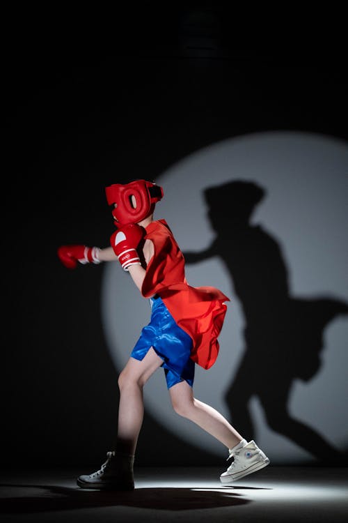 Free Child Wearing a Red Cape Doing Shadow Boxing Stock Photo