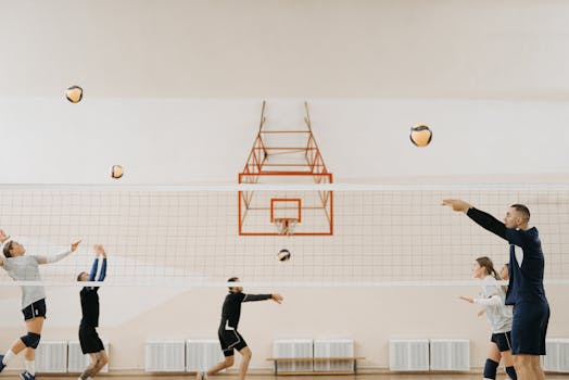 A group of young adults practicing volleyball indoors, showcasing teamwork and skill.