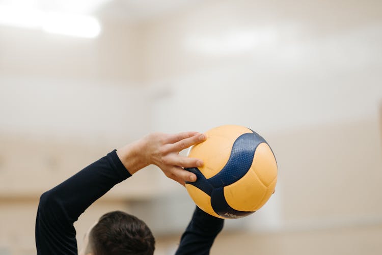 Man In Black Long Sleeve Shirt Throwing A Volleyball