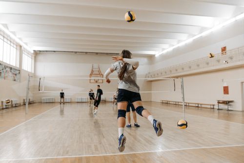 Free A dynamic volleyball match taking place in an indoor sports hall with players engaging actively. Stock Photo
