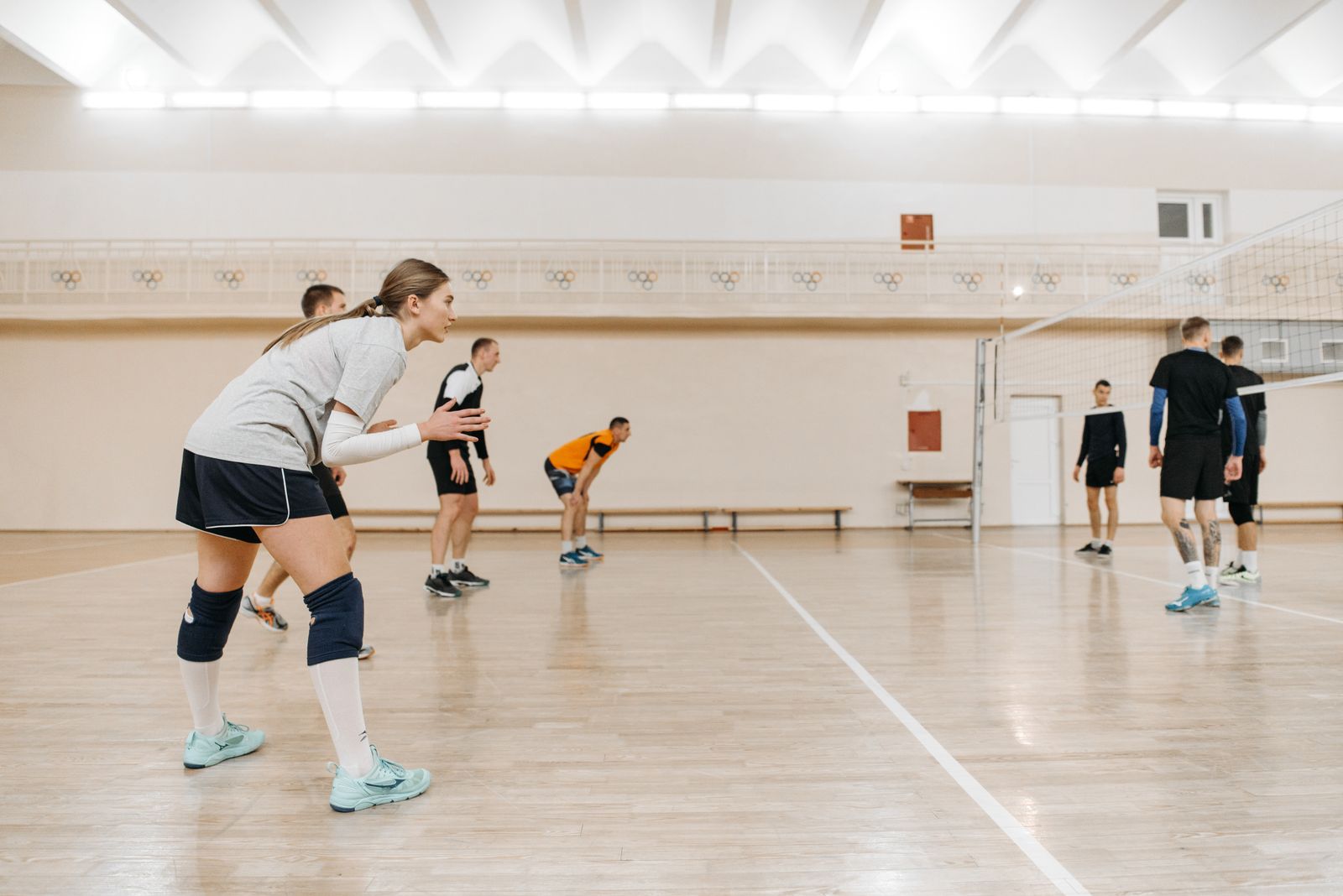 Volleyball players in overhead arm swing during game action, matching volleyball shoulder brace selection. Photo: Pexels.