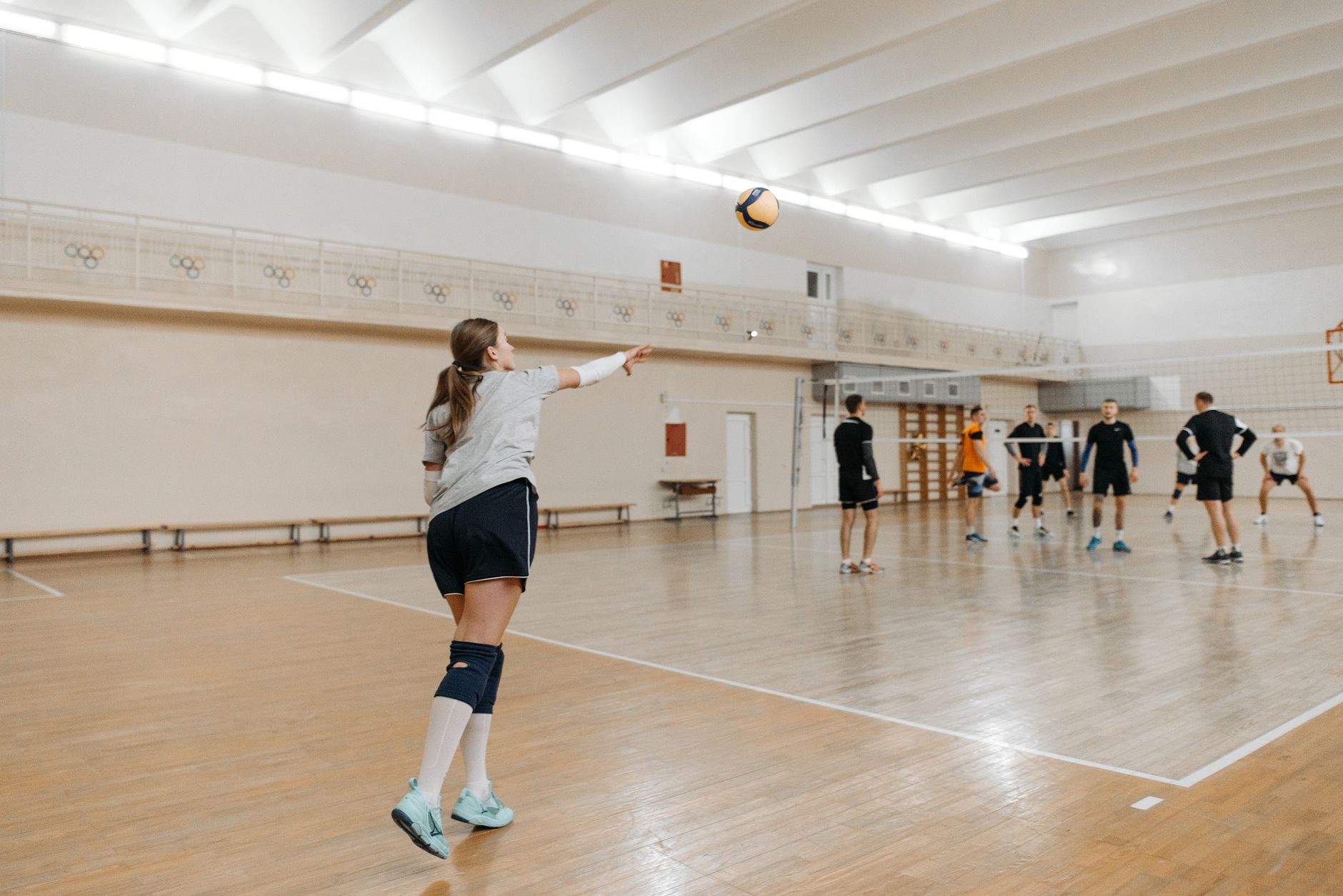 Indoor volleyball player landing on court with ankles visible for volleyball and basketball ankle brace selection. Photo: Pexels.