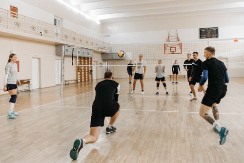 Free Eight adults play an energetic volleyball game, showcasing teamwork and athleticism on an indoor court. Stock Photo