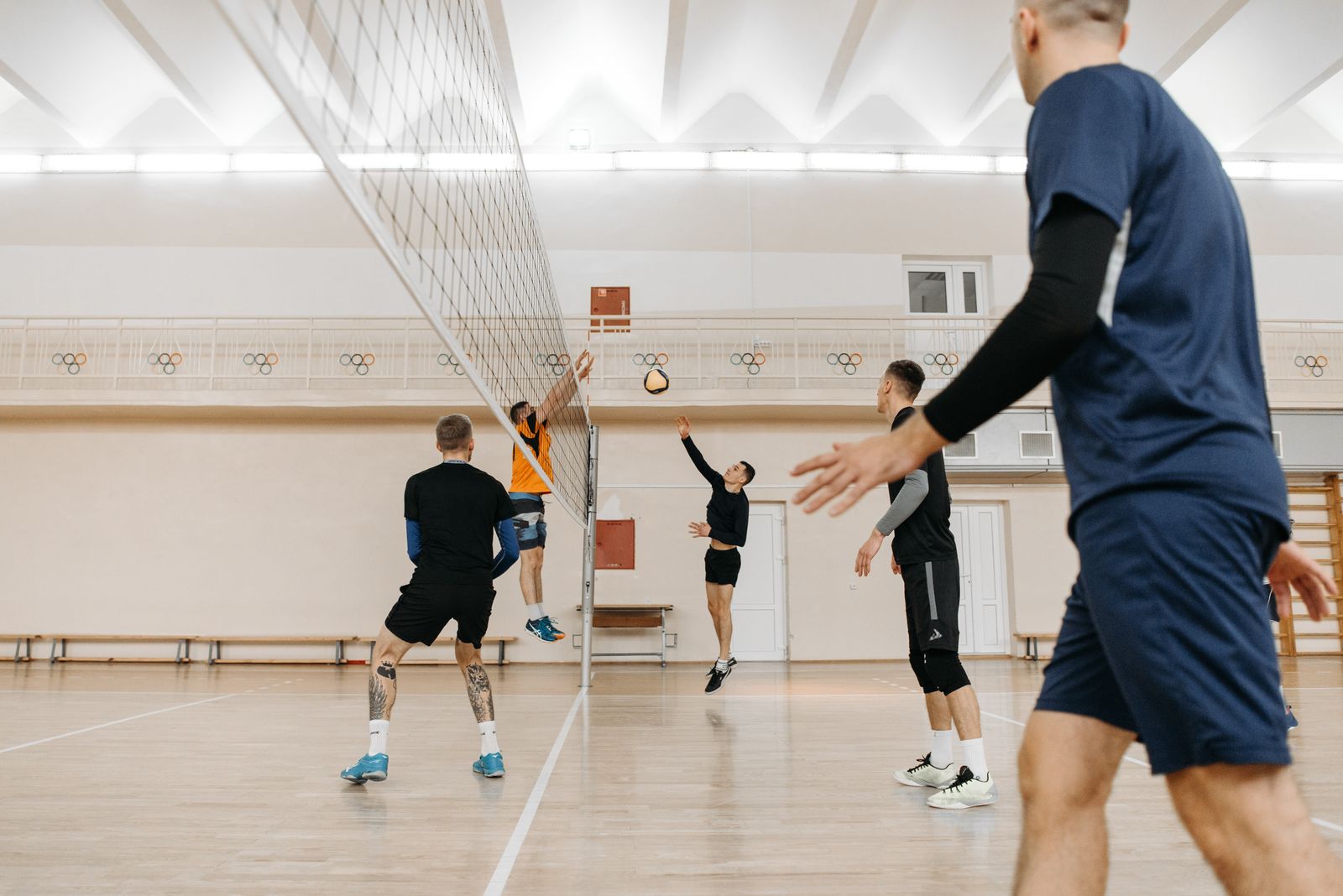 Indoor volleyball athletes jumping and landing, matching sport ankle brace selection for athletes. Photo: Pexels.