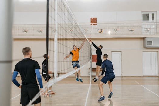 Exciting indoor volleyball match with athletes jumping to block and spike.