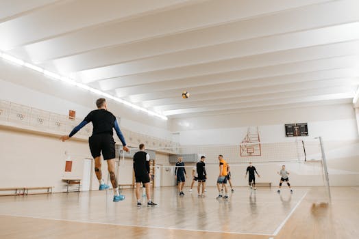 A dynamic indoor volleyball match featuring six athletes jumping and playing vigorously.