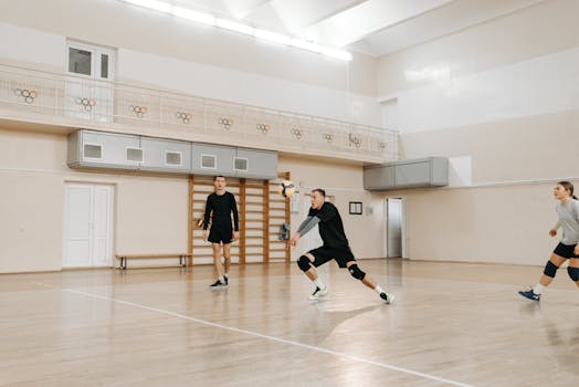 Team of athletes playing volleyball in an indoor court during a casual match.