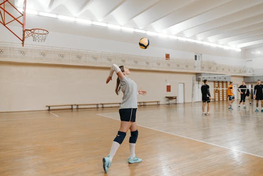 Action shot of a female athlete serving in an indoor volleyball game.