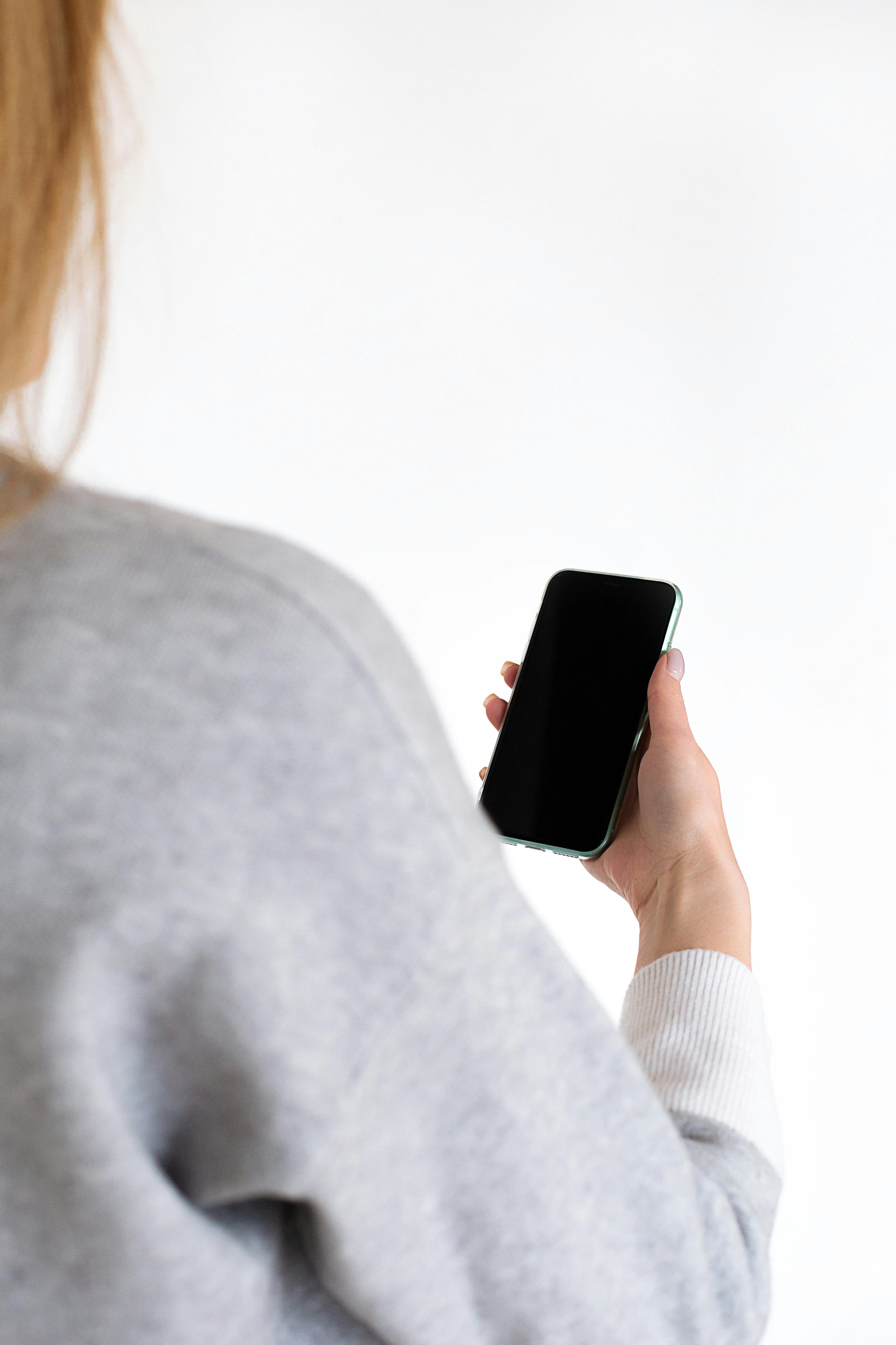 Free Close-up of a woman holding a smartphone with a black screen in her hand. Stock Photo