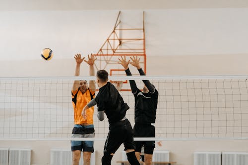 Volleyball Players Spiking a Ball Through Blockers 