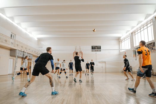 Indoor volleyball match featuring mixed-gender teams actively playing and competing.