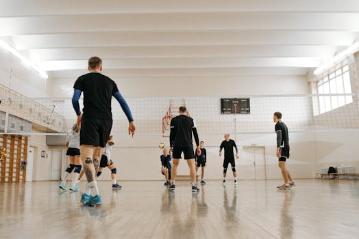 A volleyball team practicing indoors in a gym, highlighting teamwork and athletic preparation.