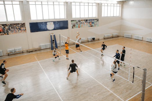 Competitive volleyball match with players jumping and spiking the ball indoors.