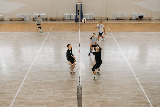 Energetic indoor volleyball game with mixed teams in an active setting.