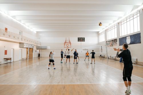 Free Adults energetically practicing volleyball indoors with a focus on teamwork. Stock Photo
