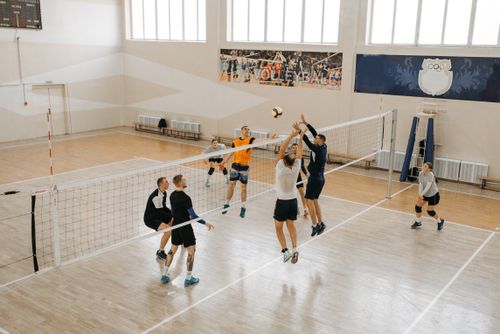 Free Dynamic scene of players jumping midair in an indoor volleyball match. Stock Photo