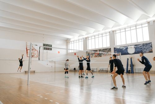 Free Dynamic indoor volleyball practice with athletes jumping and serving during an engaging match. Stock Photo