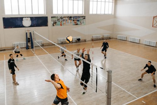Free High-energy moment captured during an indoor volleyball game with players mid-action on the court. Stock Photo