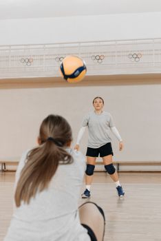 Two female athletes practicing volleyball indoors, focusing on training and teamwork.