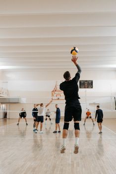 Energetic indoor volleyball game with diverse male players jumping and spiking the ball.
