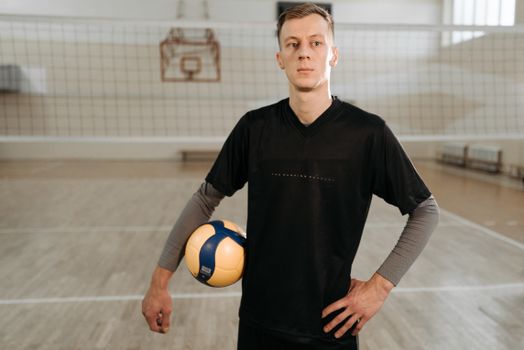 Photograph of a Man in a Black Shirt Posing with a Volleyball