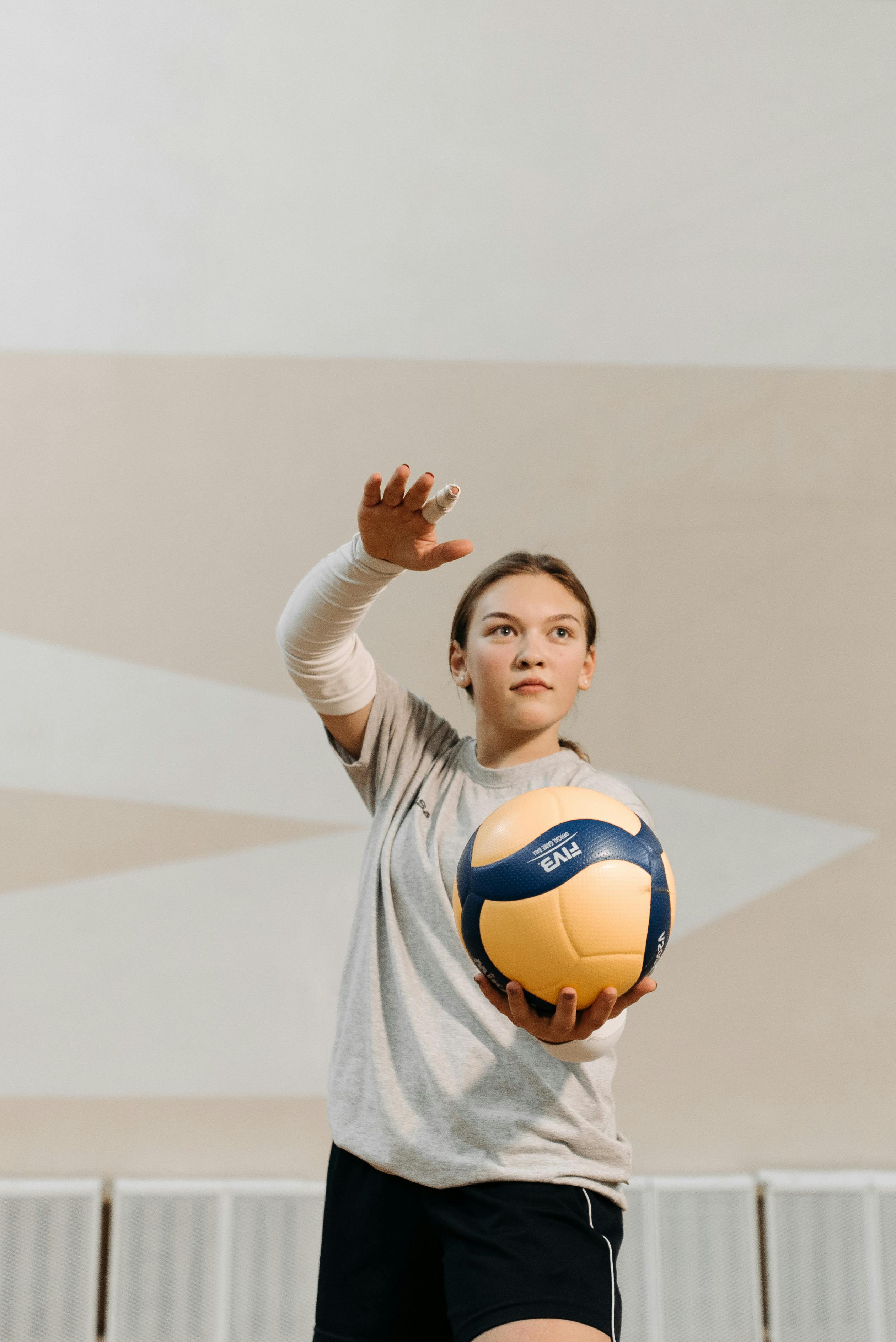 photograph of a woman in a gray shirt holding a volleyball