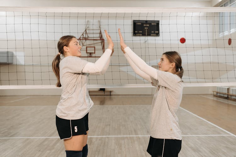 Women Doing High Five Near Volleyball Net