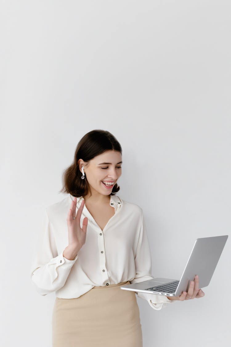 Woman Waving Her Hand While Holding A Laptop