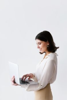 Side view of a businesswoman typing on a laptop against a white background in a studio.
