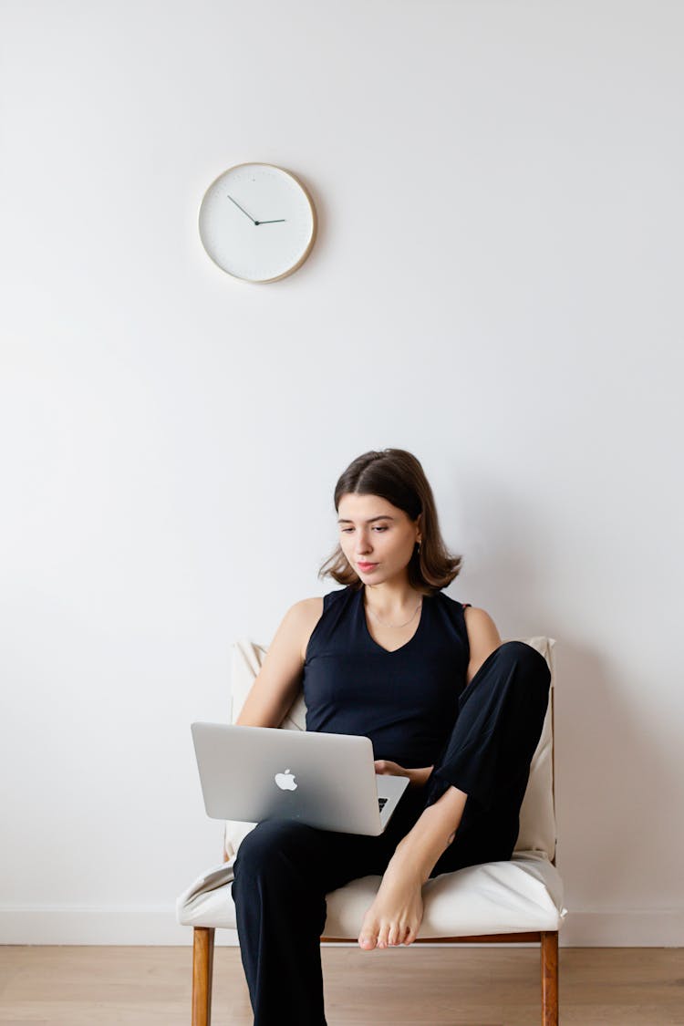 A Woman Working On A Laptop While Sitting On A Chair