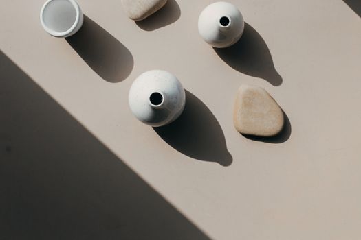 Aesthetic overhead composition of ceramic vases and stones casting artistic shadows.