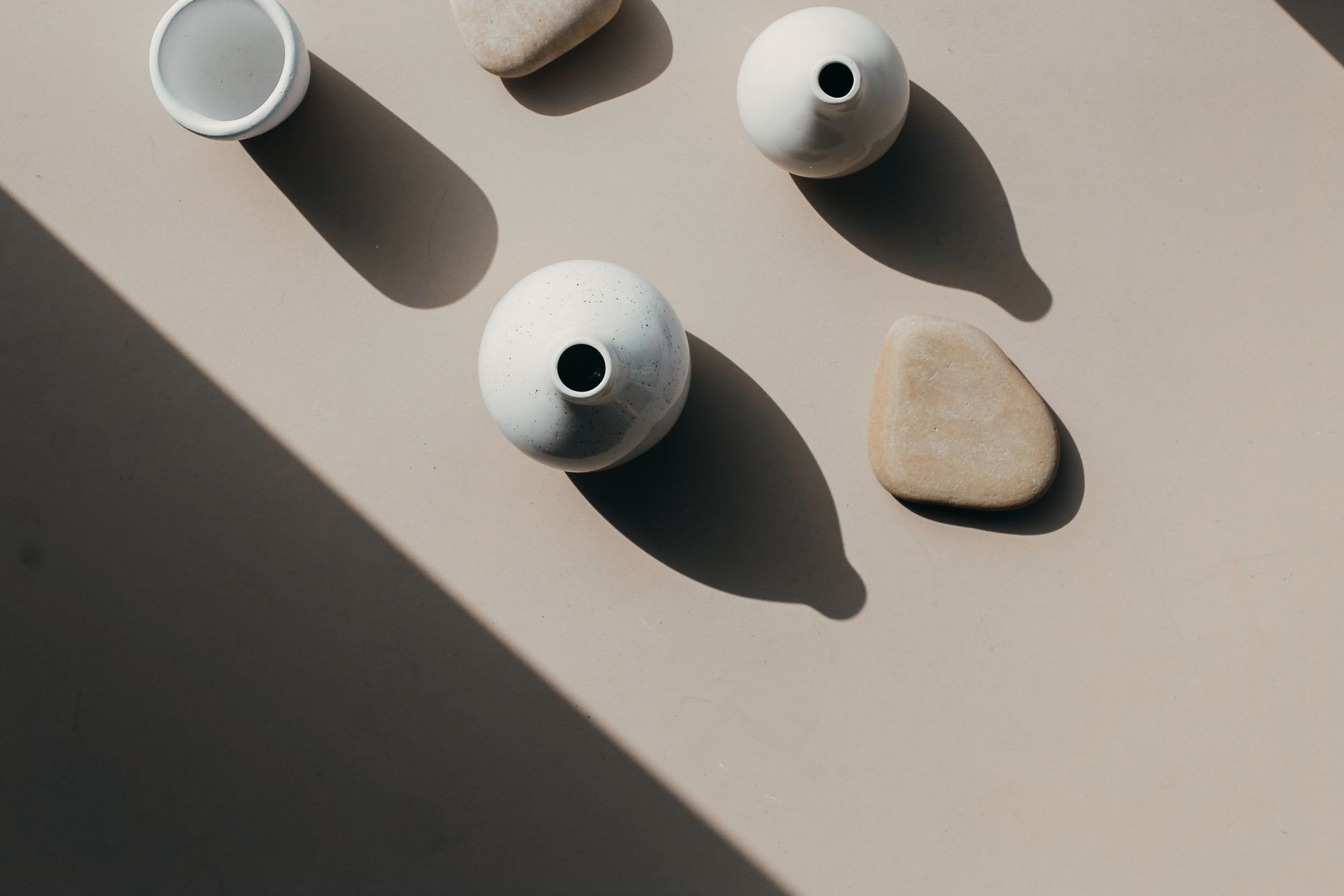 Overhead view of ceramic vases and stones casting long shadows