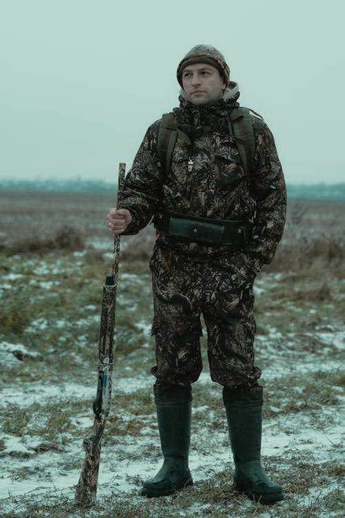 Photo of Man in Camouflage Clothing Holding a Rifle