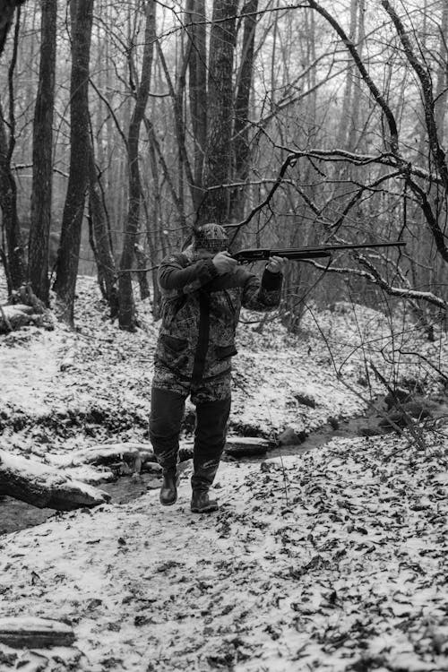 Man Walking While Aiming a Riffle 