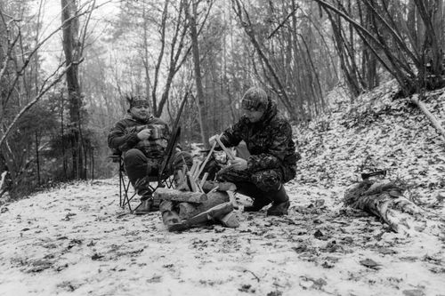 Free Two men enjoy a cozy winter camping experience in a snowy forest. Stock Photo