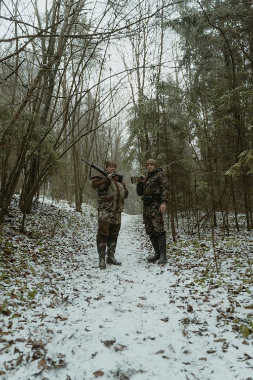 Two Men Standing in the Woods Holding Rifles