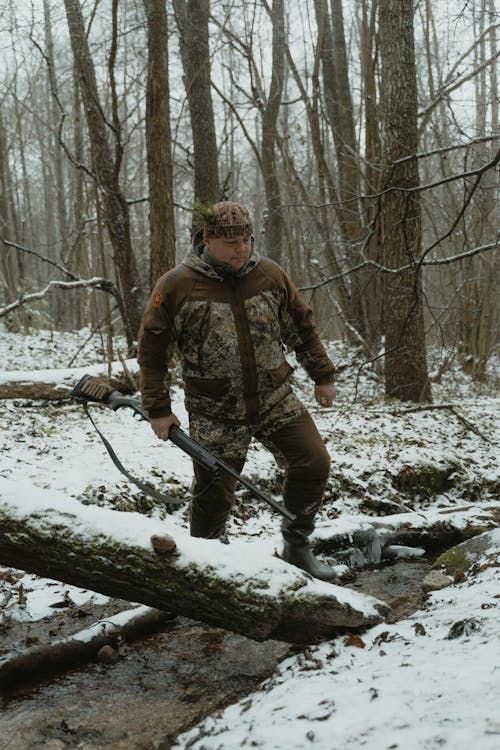 Man in Camouflage Holding a Rifle and Crossing a River