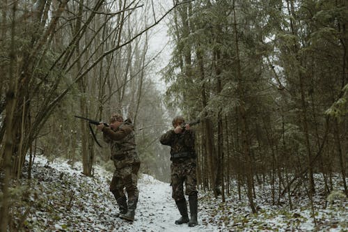 Two Men Standing on Forest Aiming Their Rifles